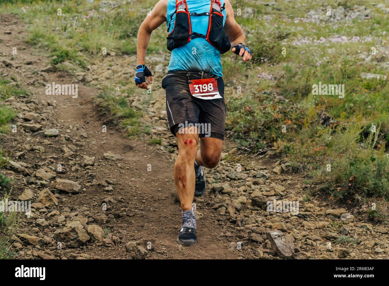 athlète coureur descendant en montagne dans la course de marathon de sentier, genou dans le sang après l'automne Banque D'Images