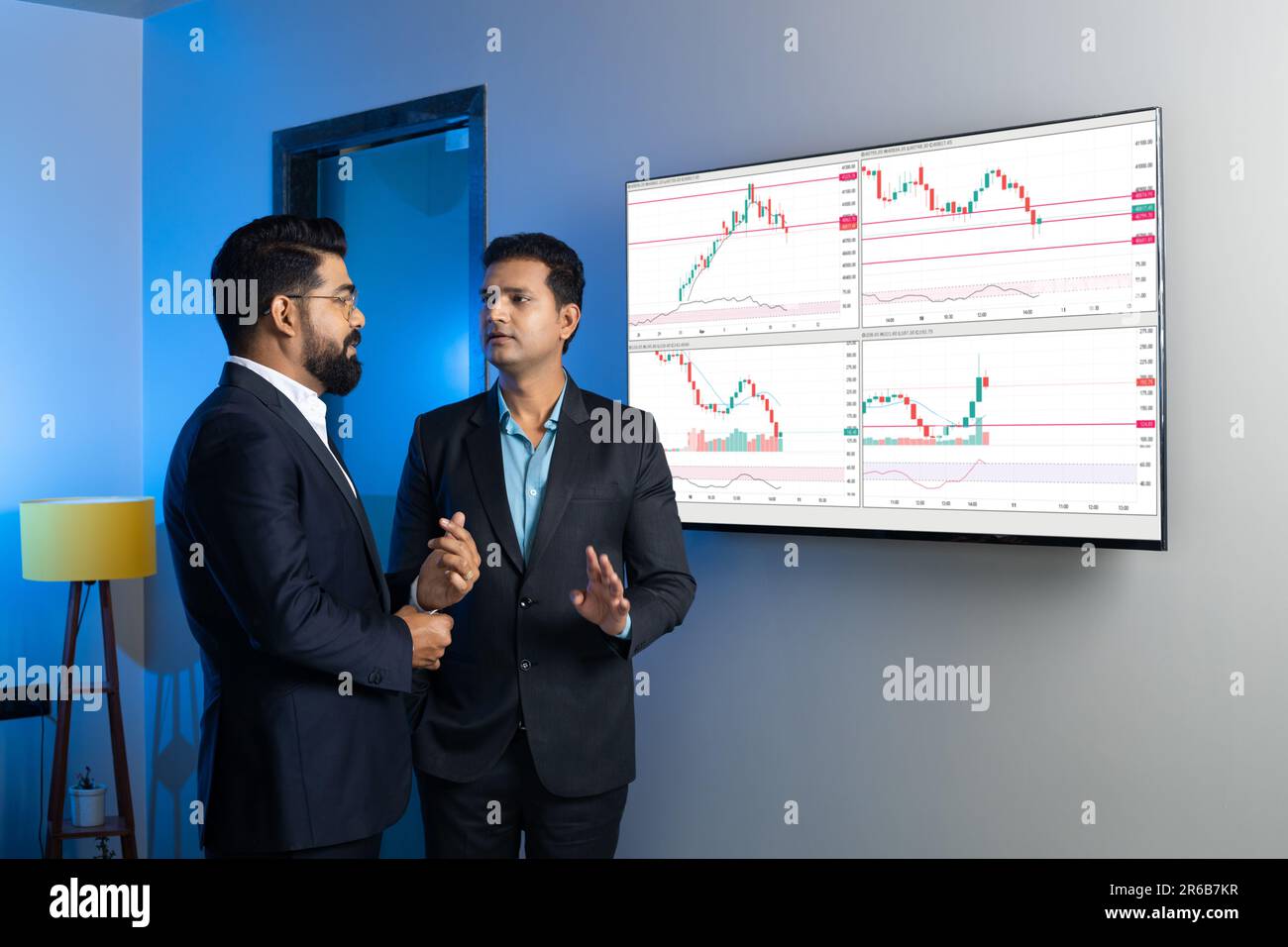 Des collègues d'hommes d'affaires indiens négociant et discutant des actions en ligne au bureau. Courtiers en Bourse regardant des graphiques d'index sur grand écran d'ordinateur. Crypto A. Banque D'Images
