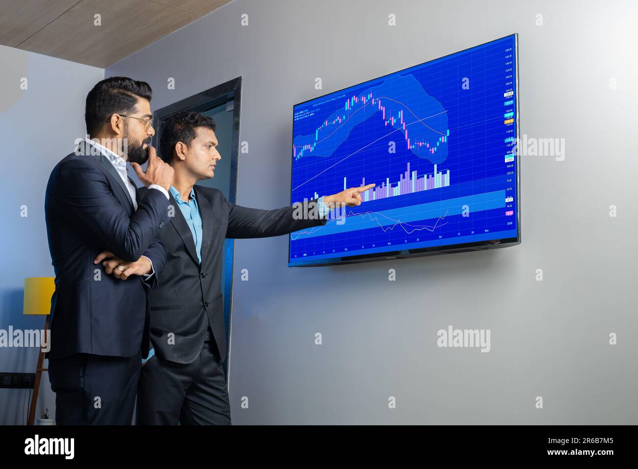 Des collègues d'hommes d'affaires indiens négociant et discutant des actions en ligne au bureau. Courtiers en Bourse regardant des graphiques d'index sur grand écran d'ordinateur. Banque D'Images