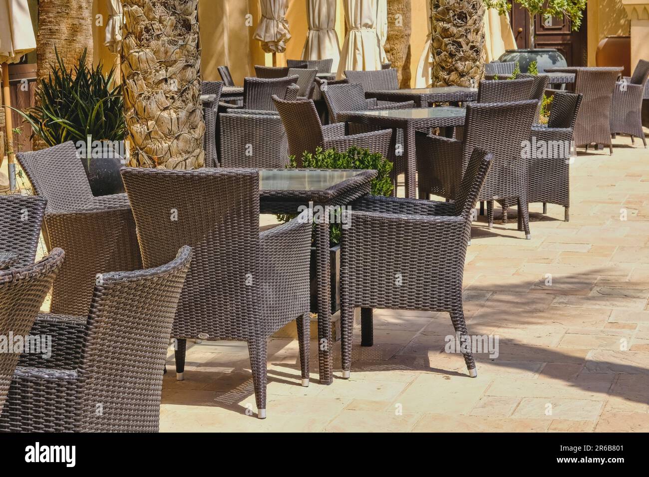 Café de rue vide en plein air avec fauteuils et tables en rotin. Chaises en osier sur la terrasse du café. Mobilier urbain moderne écologique Banque D'Images