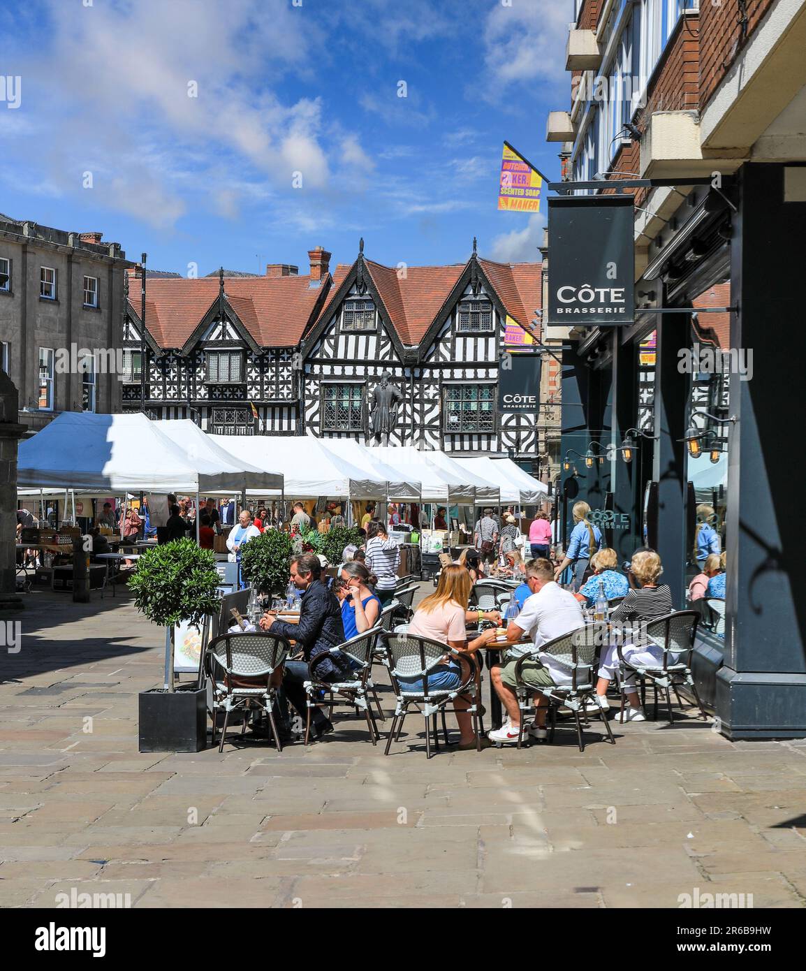 Les gens assis manger et boire dehors dans la place du marché dans le centre-ville, Shrewsbury, Shropshire, Angleterre, Royaume-Uni Banque D'Images
