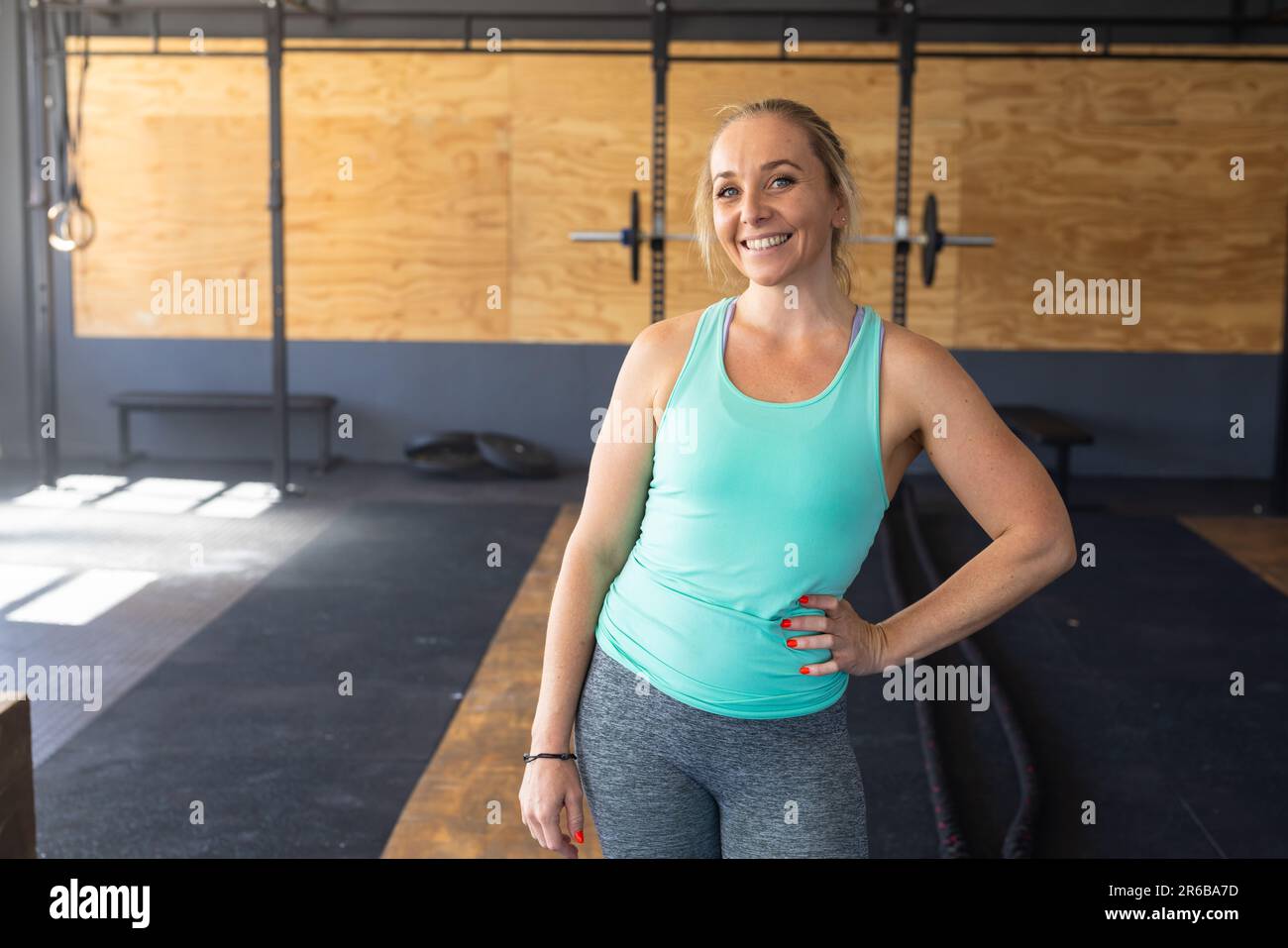 Portrait d'une jeune femme caucasienne souriante avec la main sur la hanche debout avec confiance dans le club de santé Banque D'Images