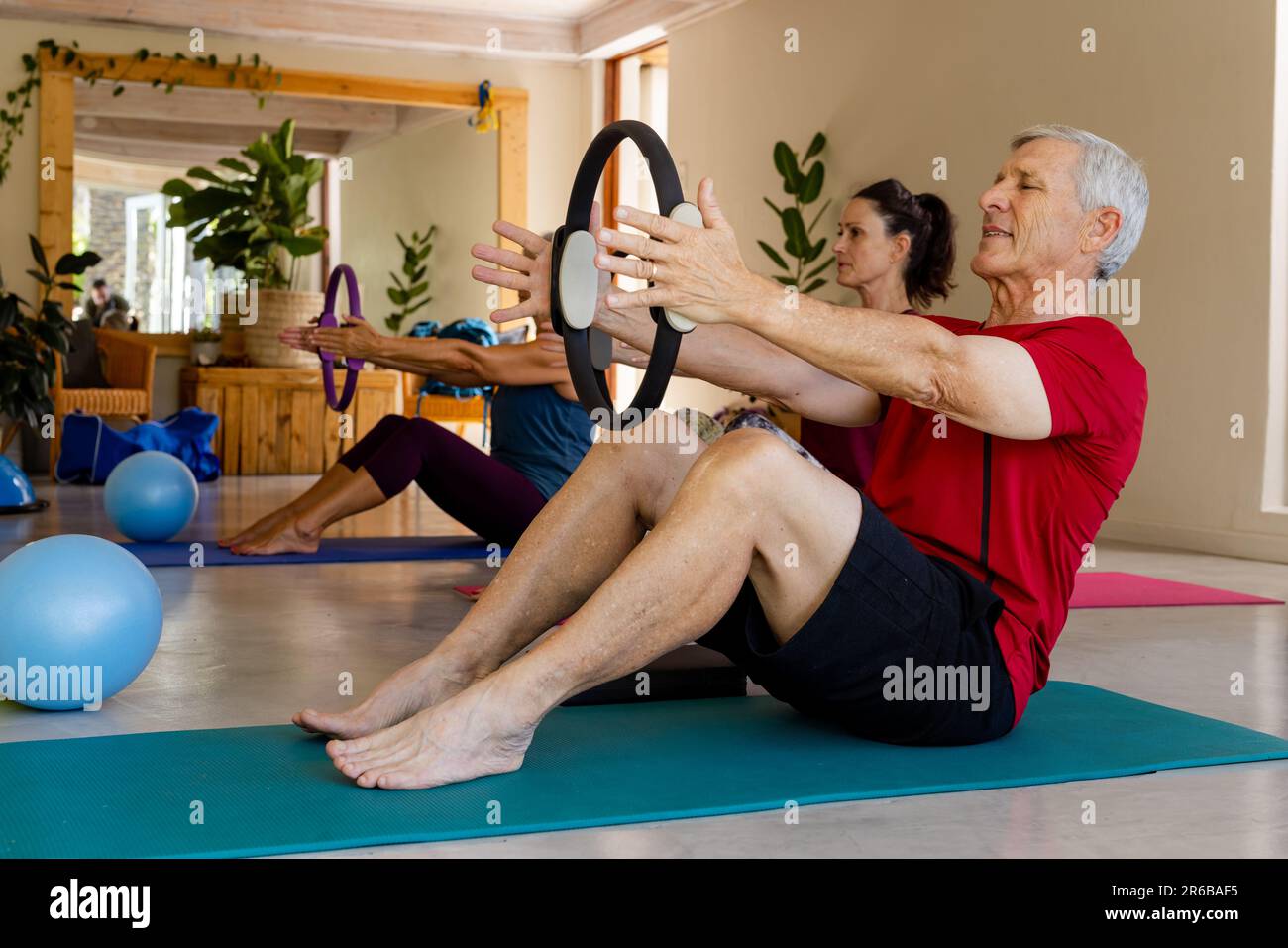 Personnes âgées caucasiennes ciblées utilisant des anneaux d'exercice dans la classe pilates avec entraîneur féminin Banque D'Images