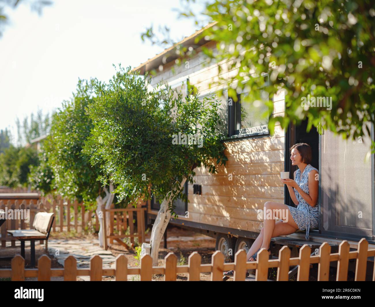 La femme boit du café, la routine du matin près de sa petite maison