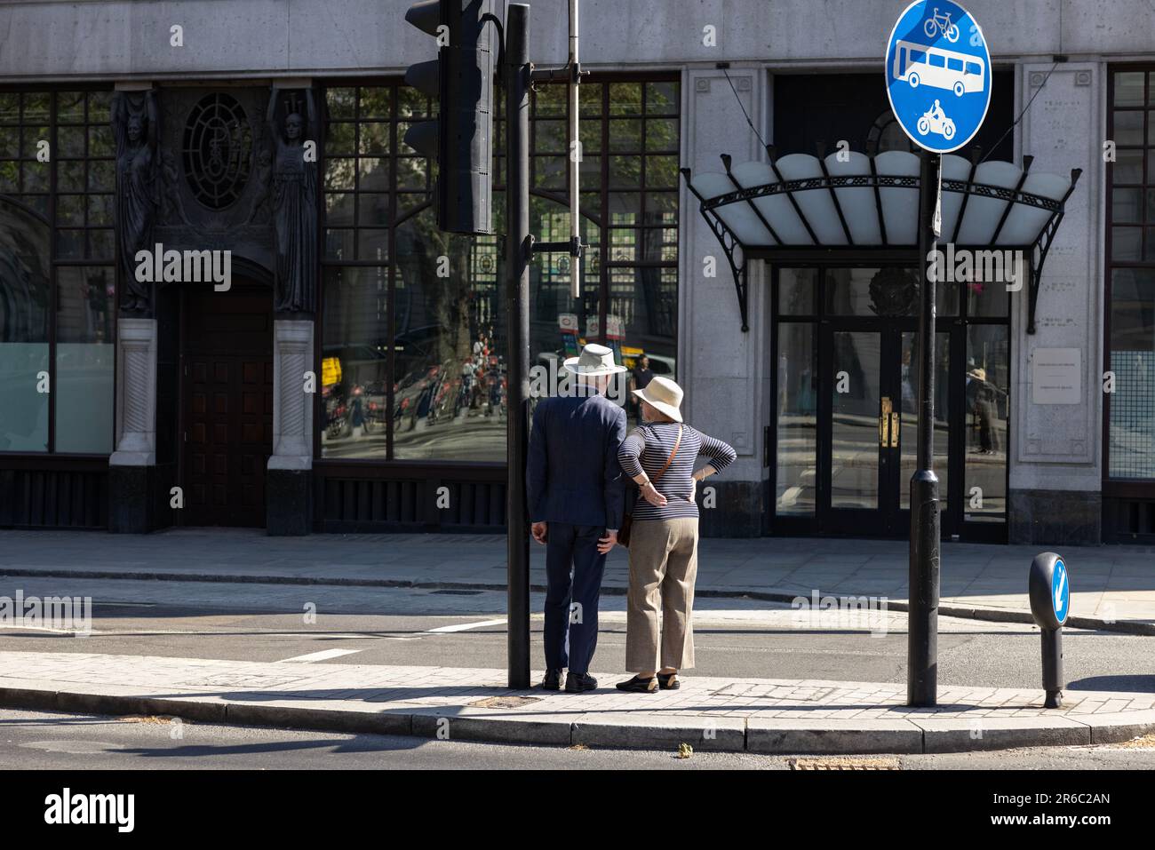 Un couple de touristes âgés à la retraite attendent de traverser la route sur Cockspur Street à côté de Trafalgar Square, West End de Londres, Angleterre, Royaume-Uni Banque D'Images