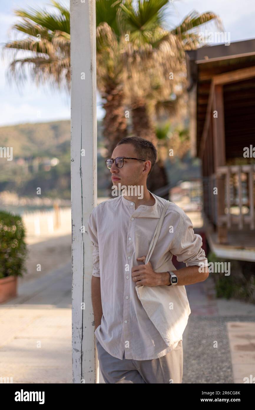 un jeune caucasien dans une chemise sans col et un pantalon de robe, se  penchant sur un bâton et tenant un sac de shopping Photo Stock - Alamy