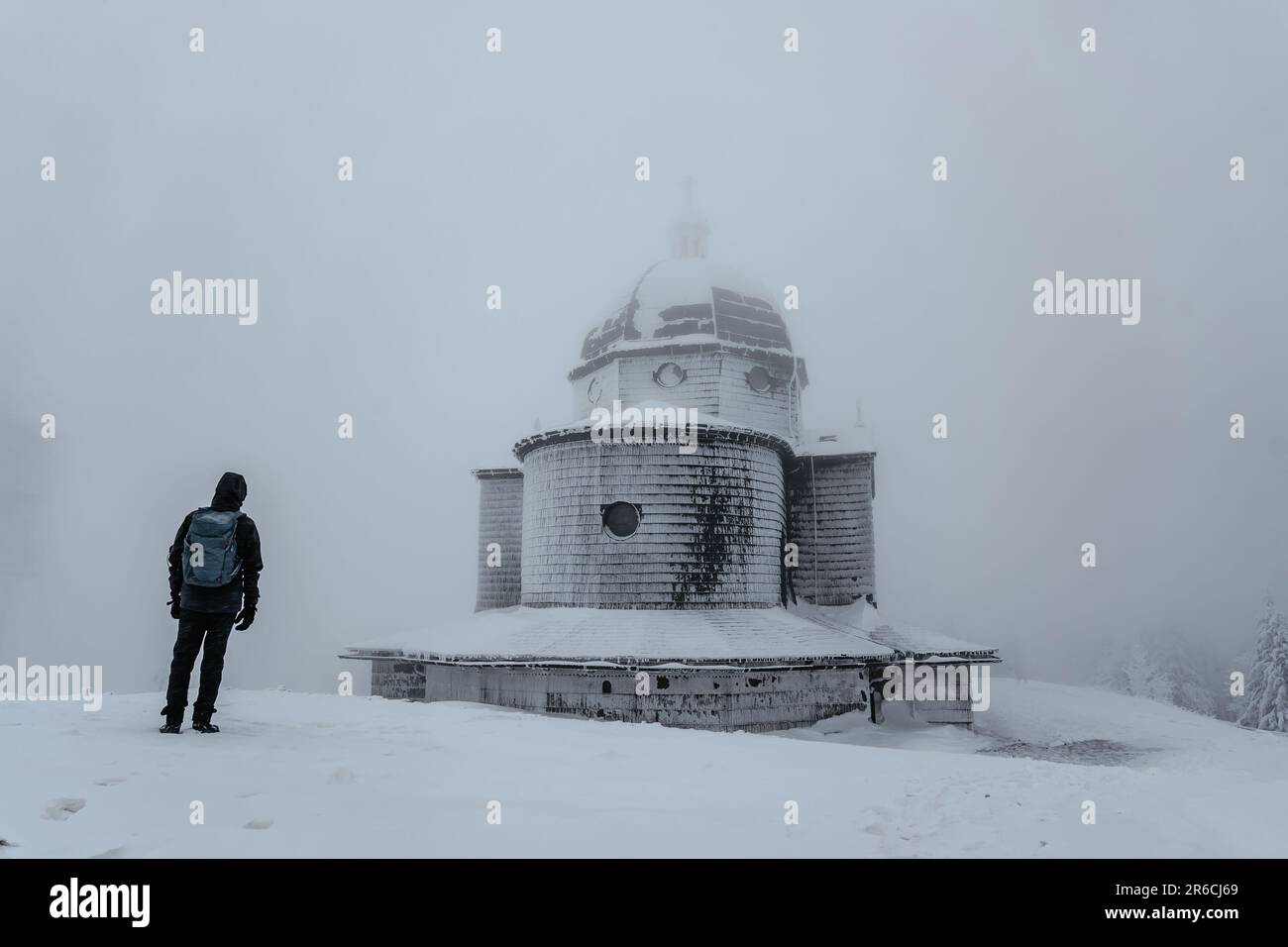 Homme solitaire debout sur la montagne Radhost regardant la chapelle de St. Cyril et Methodius,Beskids,République Tchèque.Silhouette de l'homme en paysage d'hiver,fogg Banque D'Images