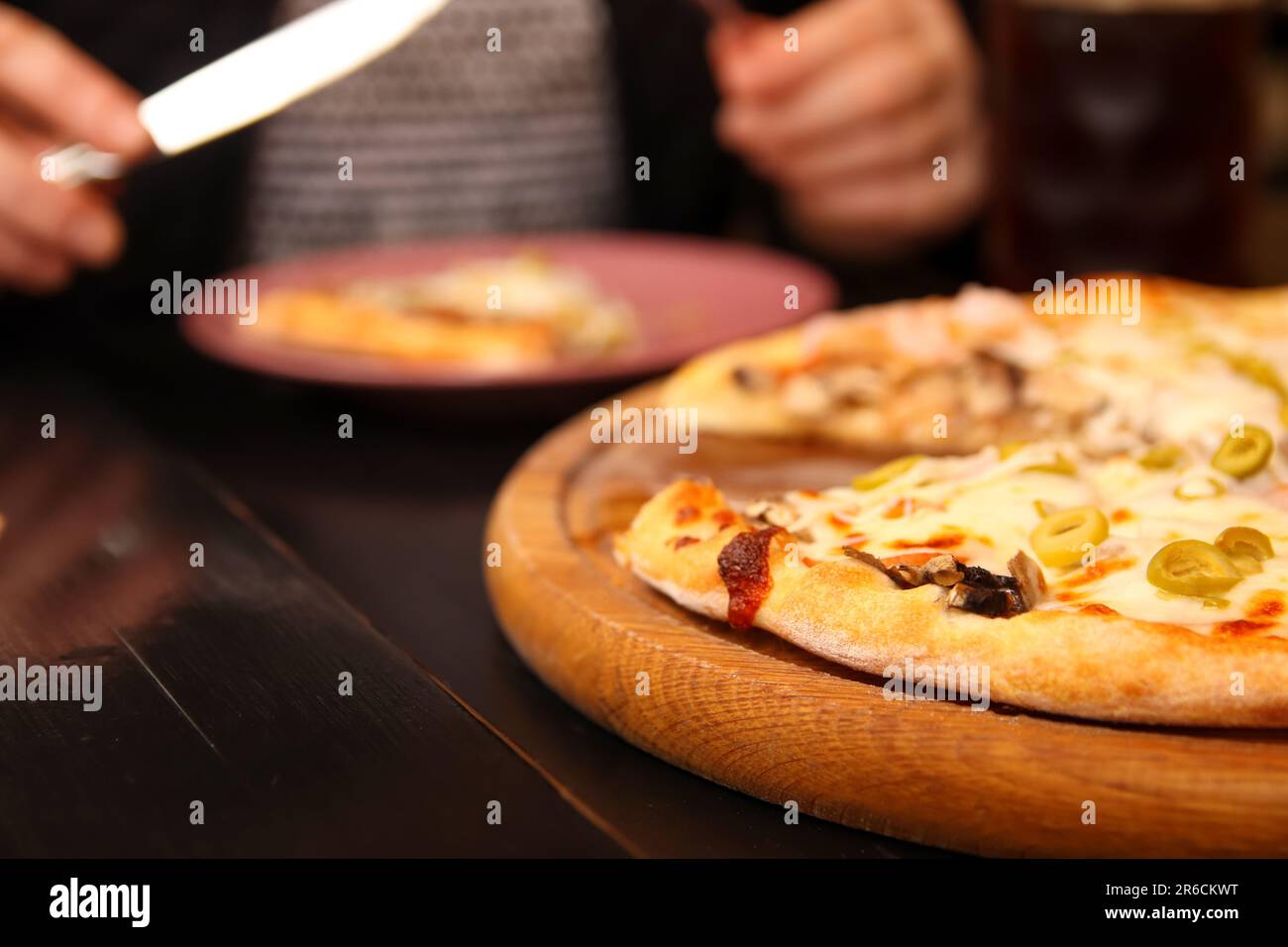 Délicieuse pizza italienne aux olives vertes, fromage Mozzarella fondu et basilic frais sur une table. Gros plan, pizzeria vibes Banque D'Images