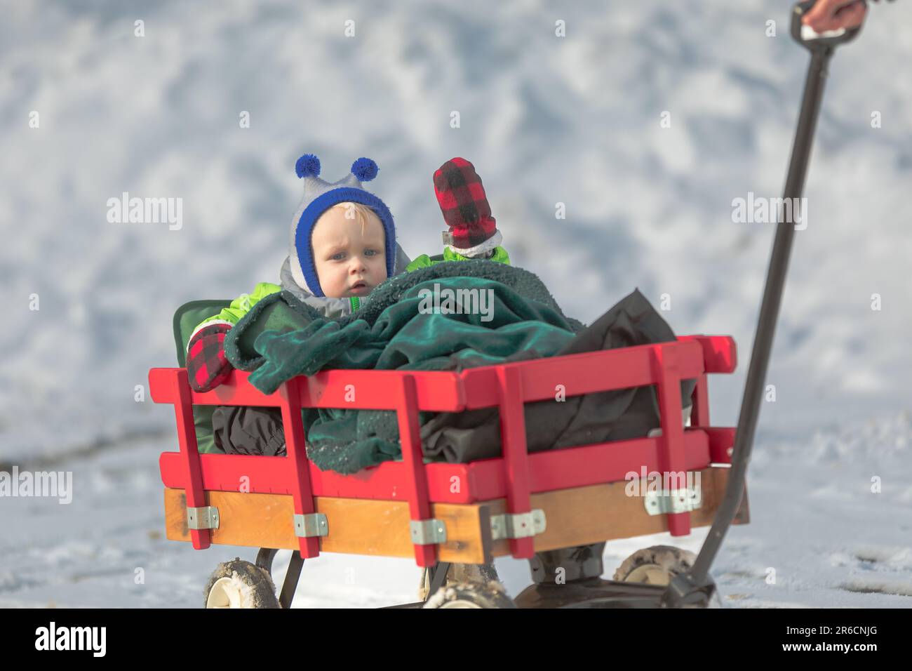 Un tout-petit se déonde d'un buggy qui traverse la neige Banque D'Images