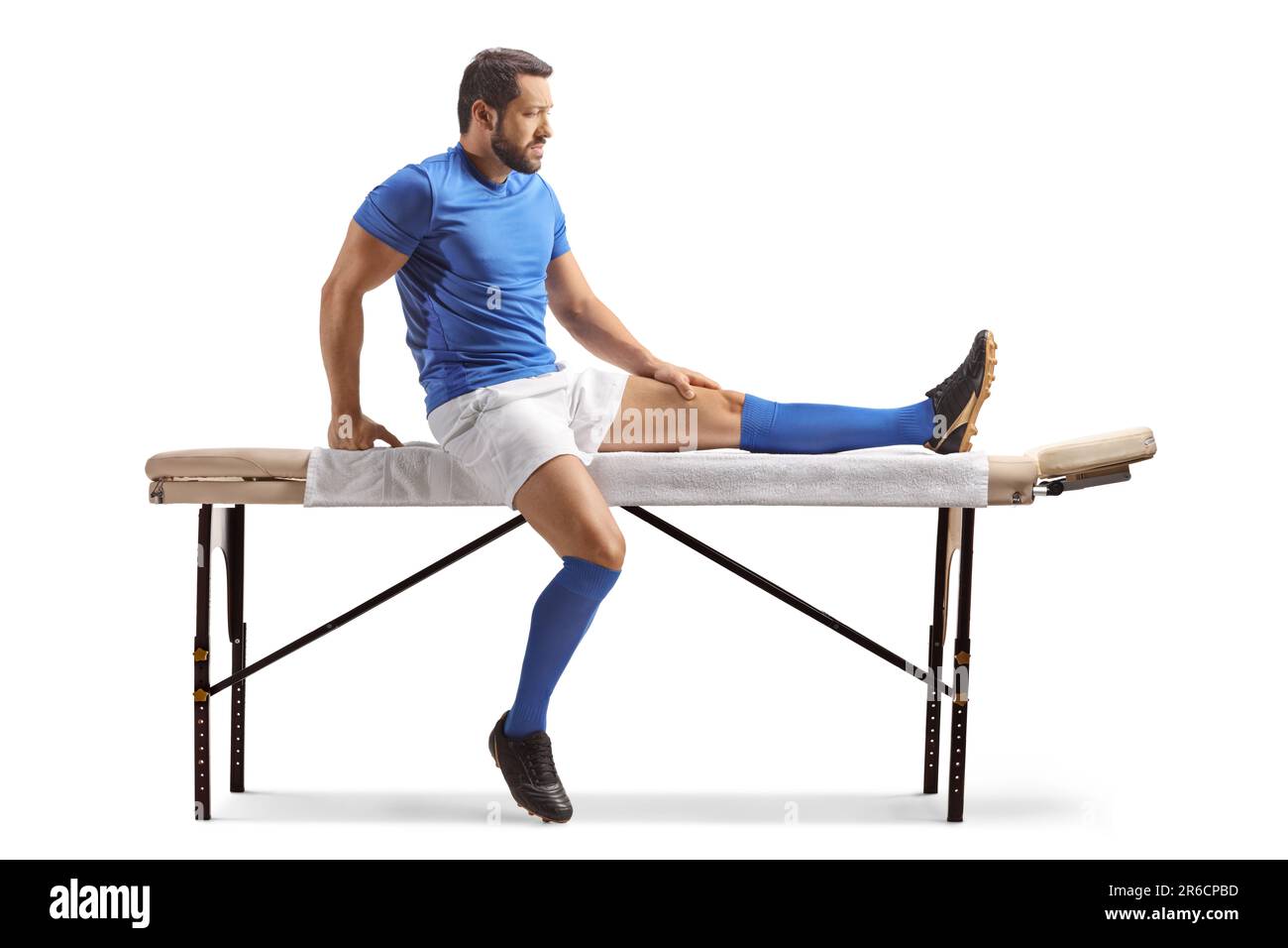 Joueur de football assis sur un lit de massage isolé sur fond blanc Banque D'Images