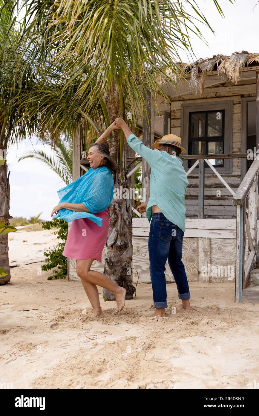 Gai caucasien mari senior dansant avec femme à la plage à l'extérieur de chalet en bois Banque D'Images