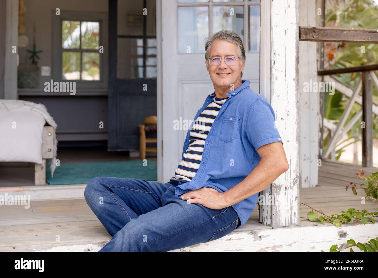 Portrait d'un homme caucasien âgé souriant assis sur des marches à l'extérieur du cottage en bois Banque D'Images