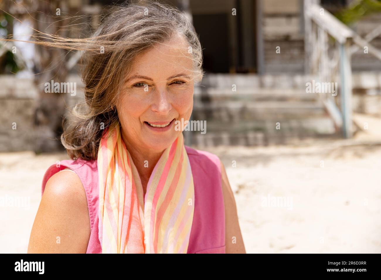 Portrait en gros plan d'une femme caucasienne souriante avec foulard autour du cou assis à la plage Banque D'Images