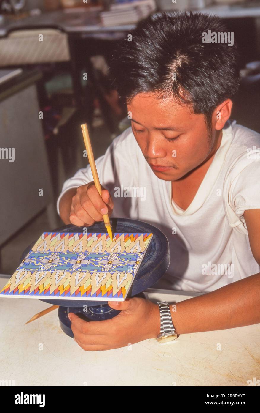 Un artiste masculin peint des carreaux dans une usine de Lampang, la troisième plus grande ville du nord de la Thaïlande. Banque D'Images