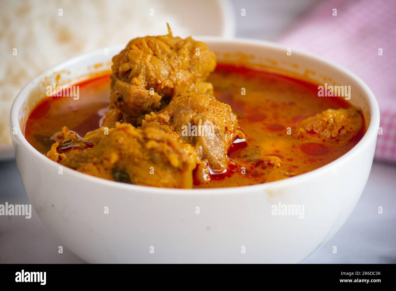 Sauce au poulet épicée dans un bol. Curry de poulet avec riz en arrière-plan Banque D'Images