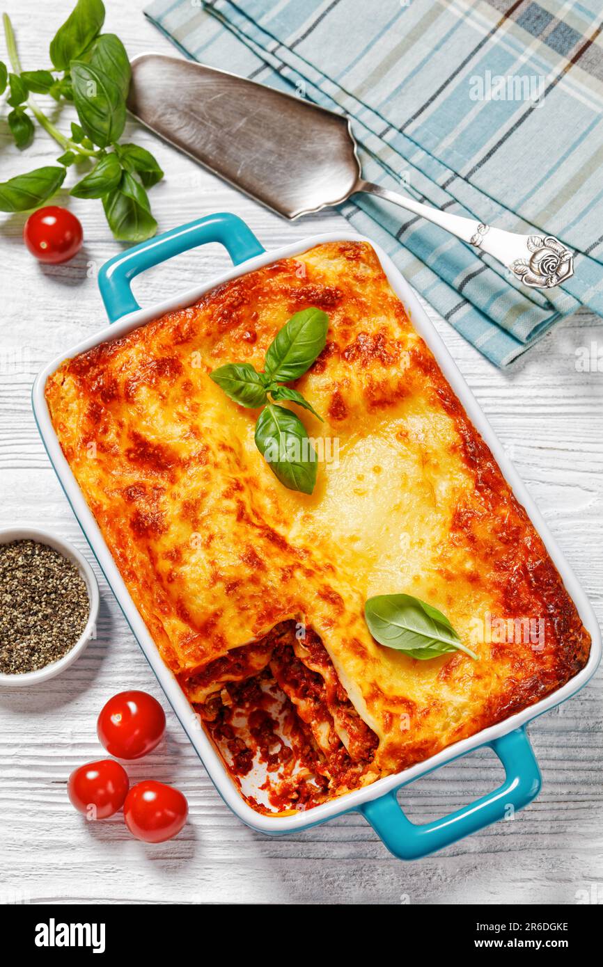 lasagnes al forno, lasagnes de bœuf italien avec du bœuf haché, sauce marinara, nouilles de pâtes et fromage ricotta dans un plat de cuisson sur table en bois blanc, Banque D'Images