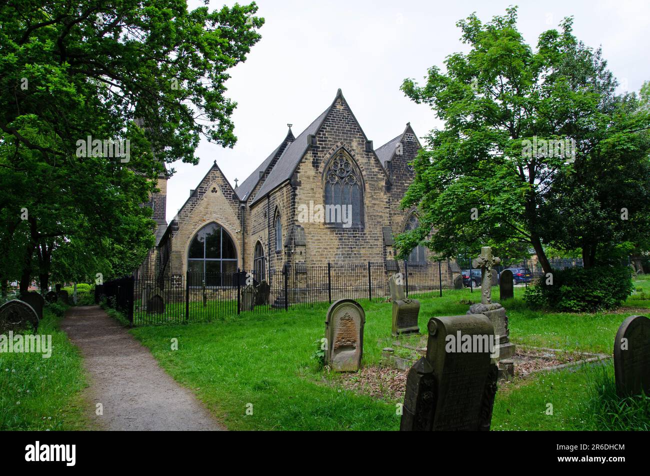 Image plein cadre du cimetière parmi les arbres et les arbustes et l'église en arrière-plan Banque D'Images