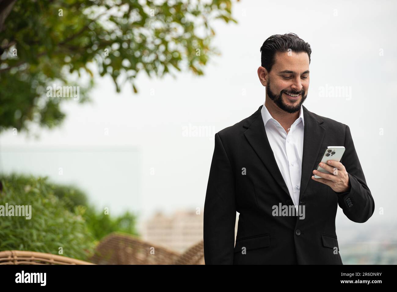 Portrait d'un homme d'affaires beau à l'extérieur sur le toit en utilisant la photo horizontale du téléphone Banque D'Images