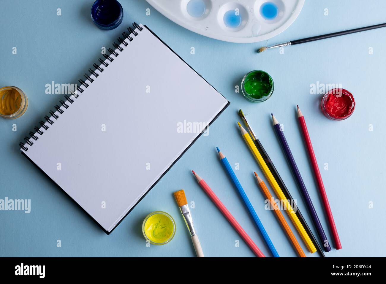 Gros plan de peintures, crayons, carnets et pinceaux avec espace de copie sur fond bleu. Retour à l'école, art, peinture, matériel scolaire, apprentissage, schoo Banque D'Images