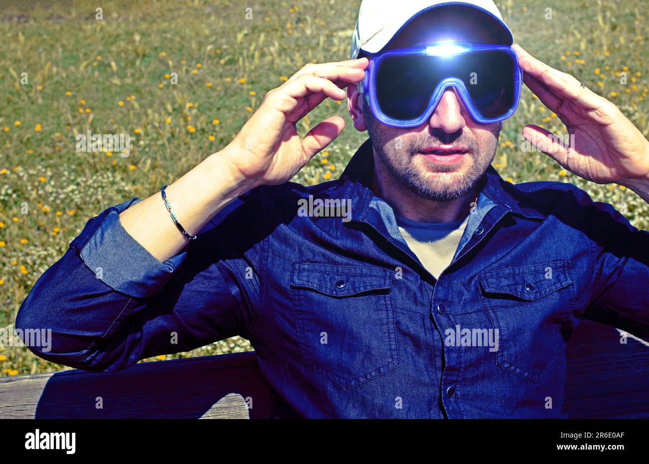 Jeune homme de la nature portant des lunettes de réalité augmentée. Homme adulte s'amusant avec des lunettes AR. Lecture. Jour. Banque D'Images