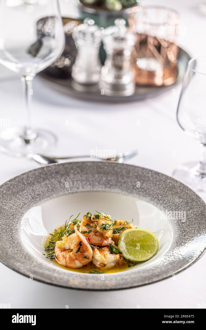 Crevettes grillées sur un beurre fondu avec de l'ail, des herbes et du Chili avec une tranche de lime. Banque D'Images