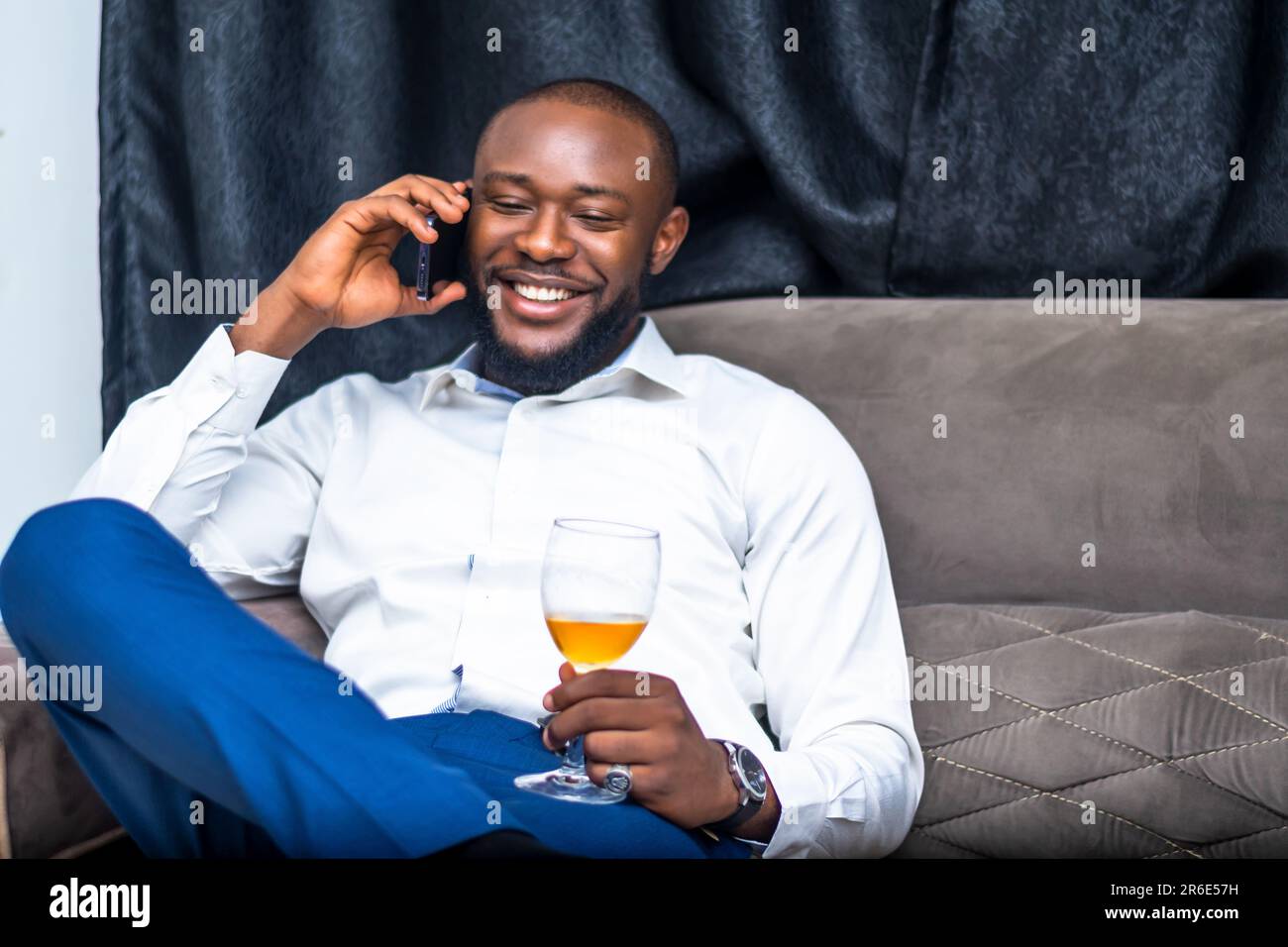 jeune homme excité communiquant avec un téléphone portable tenant un wineglass Banque D'Images