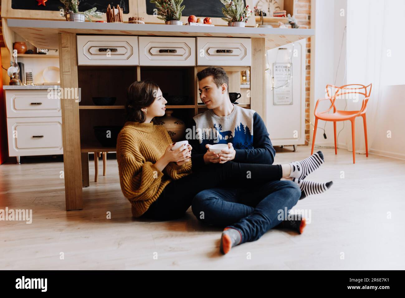 couple buvant du café assis sur le sol dans la cuisine avant noël Banque D'Images
