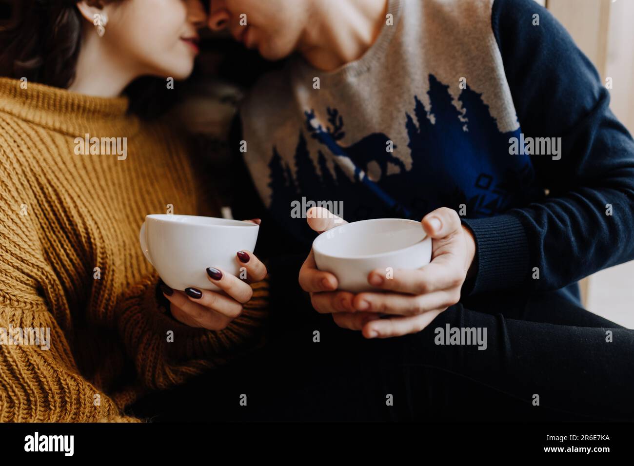 couple buvant du café assis sur le sol dans la cuisine avant noël Banque D'Images