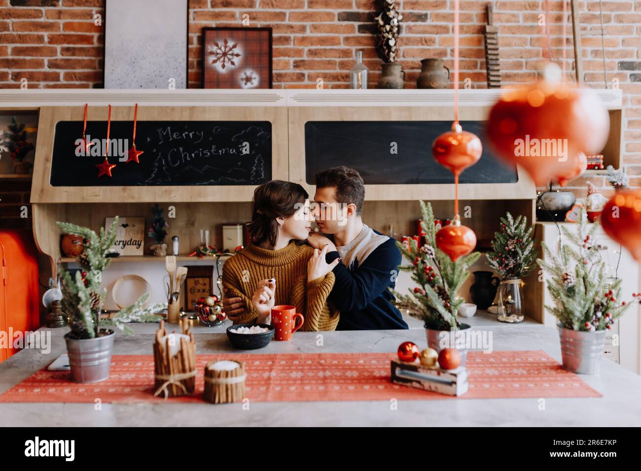 le couple se serre dans ses bras en étant assis dans la cuisine au milieu de noël Banque D'Images
