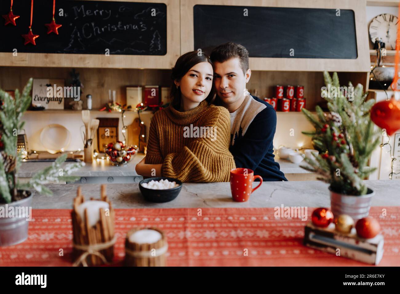 le couple se serre dans ses bras en étant assis dans la cuisine au milieu de noël Banque D'Images