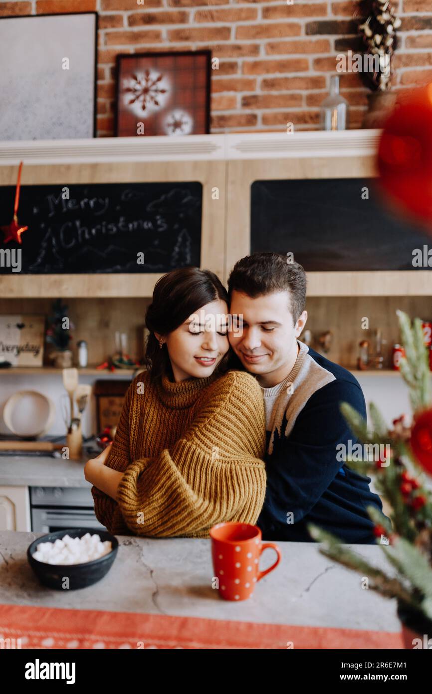 Le couple est enserrer tout en étant assis dans la cuisine au milieu de Noël Banque D'Images