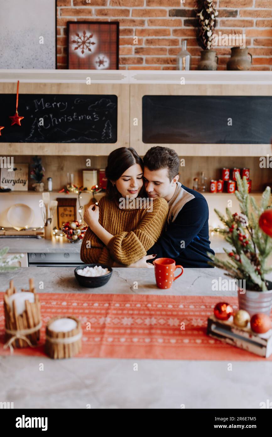 Le couple est enserrer tout en étant assis dans la cuisine au milieu de Noël Banque D'Images