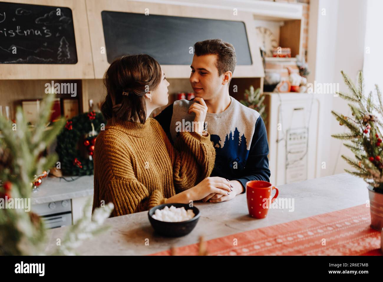 le couple se serre dans ses bras en étant assis dans la cuisine au milieu de noël Banque D'Images