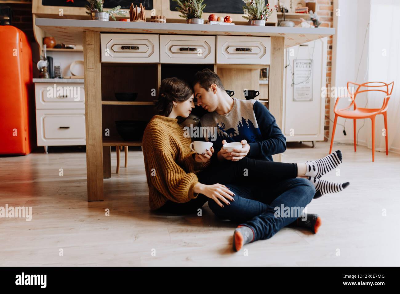 couple buvant du café assis sur le sol dans la cuisine avant noël Banque D'Images