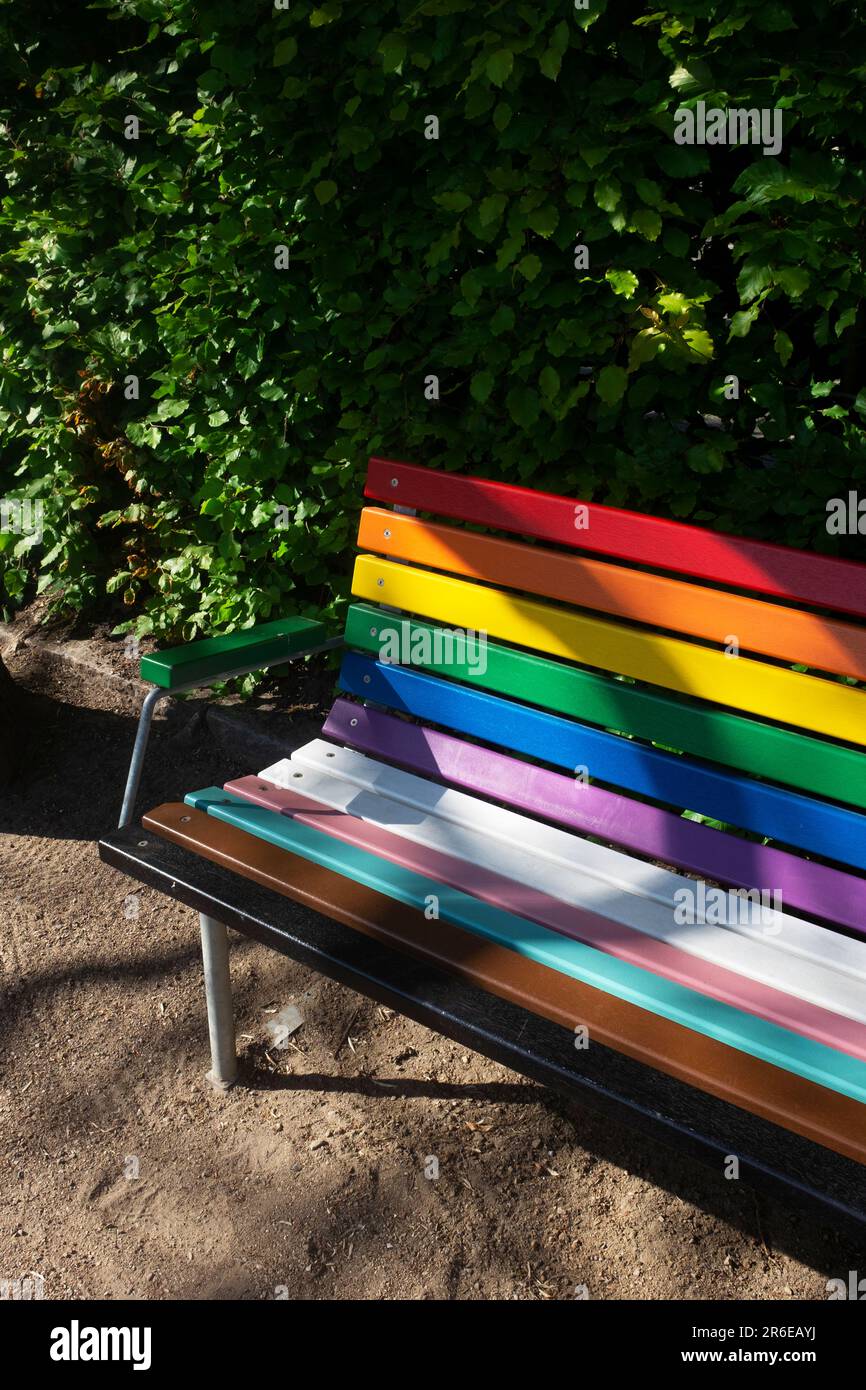 Un banc peint avec des couleurs arc-en-ciel dans un parc Banque D'Images