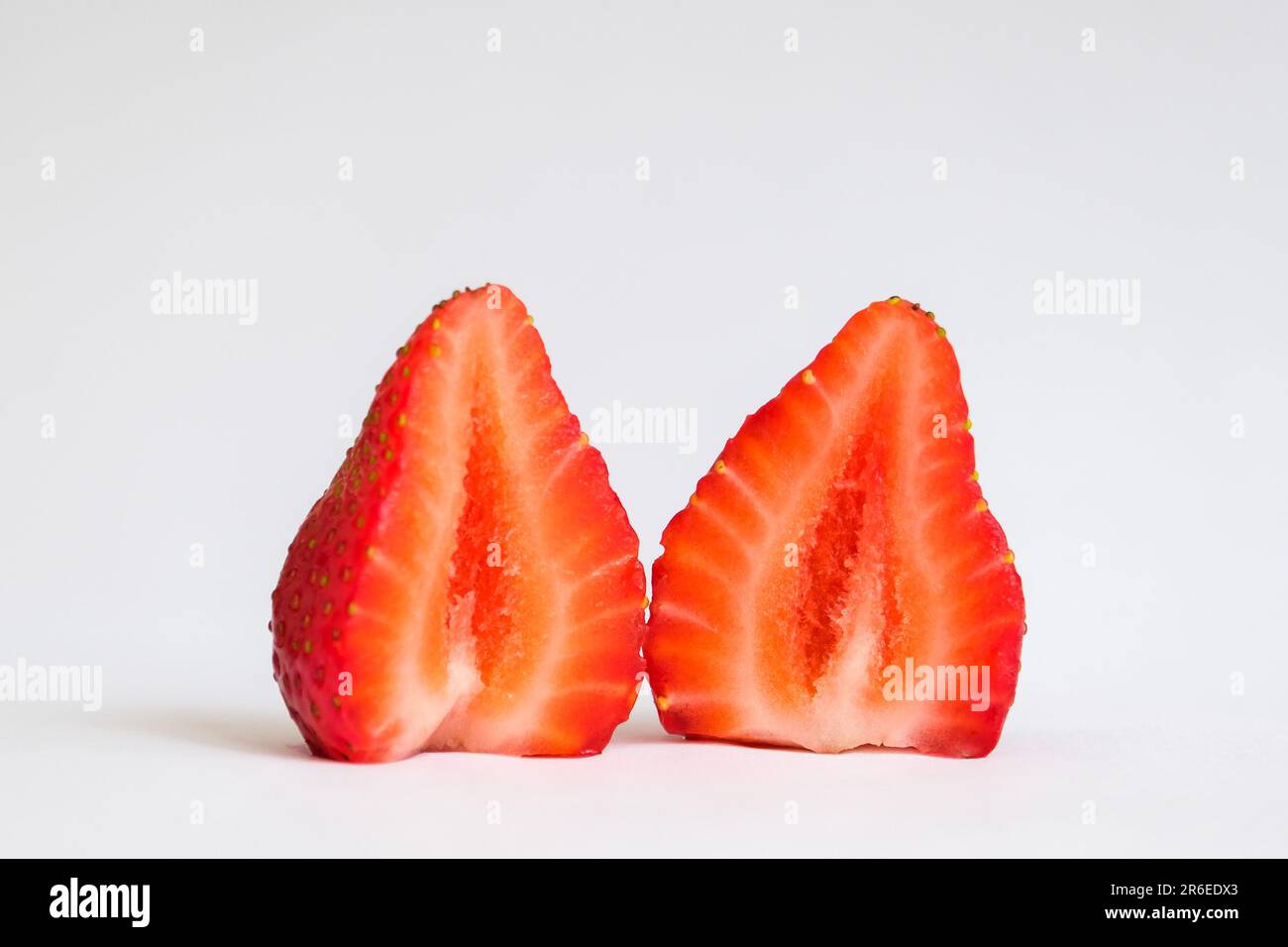 Gros plan macro-rouge frais à l'intérieur de la moitié de la tranche de fruits de fraise avec un fond blanc isolé. Fermeture sélective de fraise. Fruits coupés aux fraises. Banque D'Images