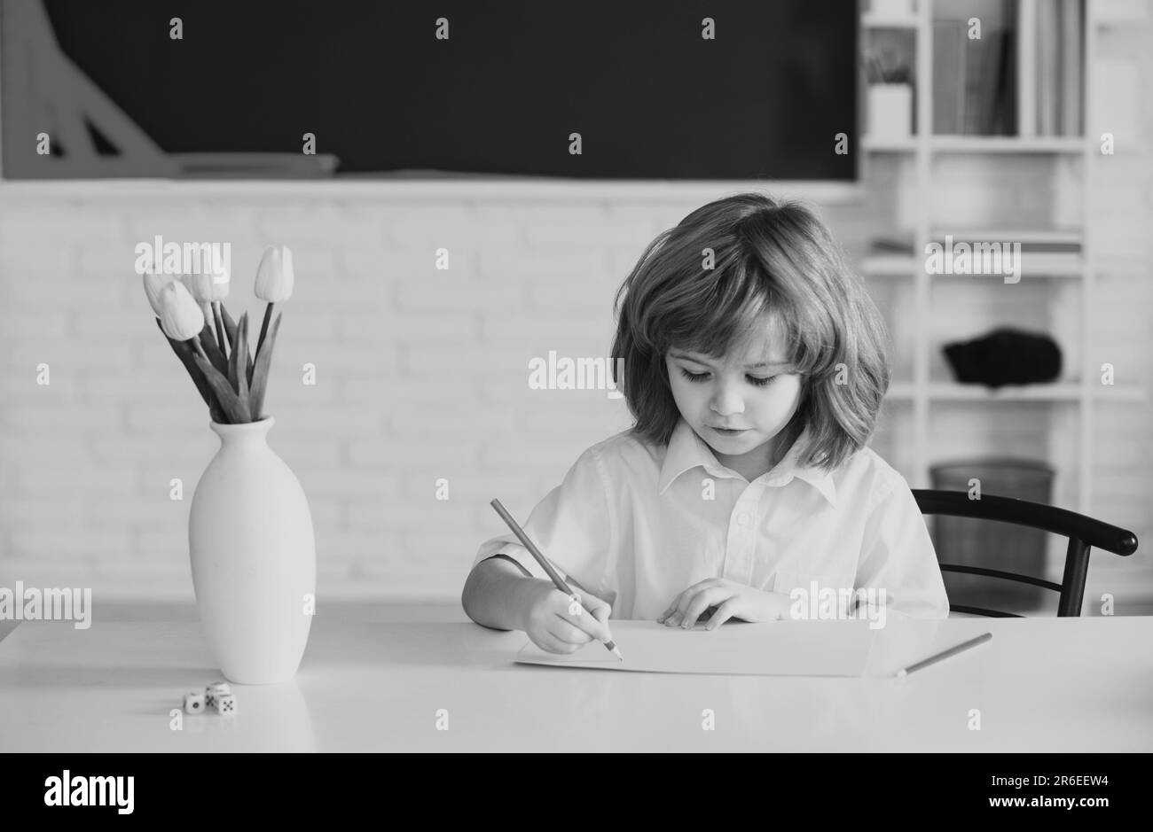 Un écolier fait ses devoirs. L'enfant de l'école contre le tableau noir vert. Se prépare à l'école. Banque D'Images