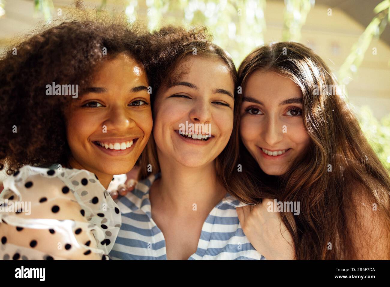 Gros plan portrait de trois jolies adolescentes de différentes nationalités dans des vêtements décontractés posent à l'appareil photo et embrasse. Souriant drôles filles h Banque D'Images
