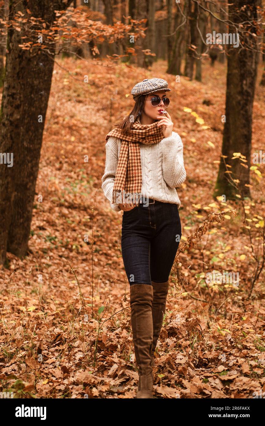 Détente fumeur. La femme aime fumer seule. Fumeur seul. L'automne est là. Jolie femme en chapeau et lunettes de soleil fume cigarette forêt fond Banque D'Images