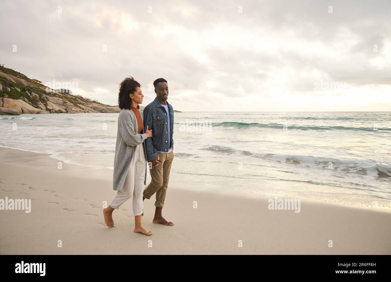 Jeune couple multiethnique tenant les mains et marchant le long d'une plage Banque D'Images