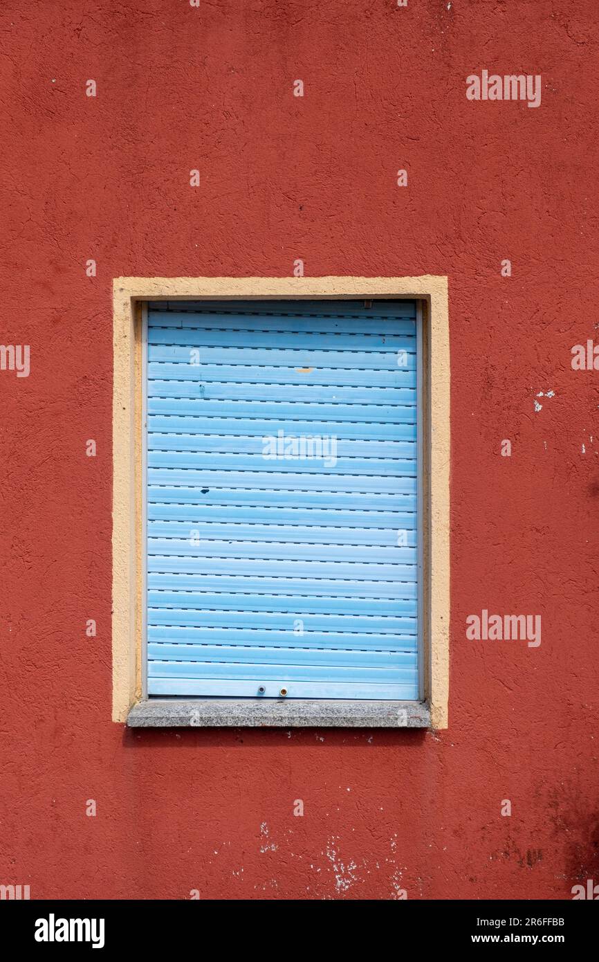 fenêtre avec obturateur bleu sur un mur peint en rouge Banque D'Images