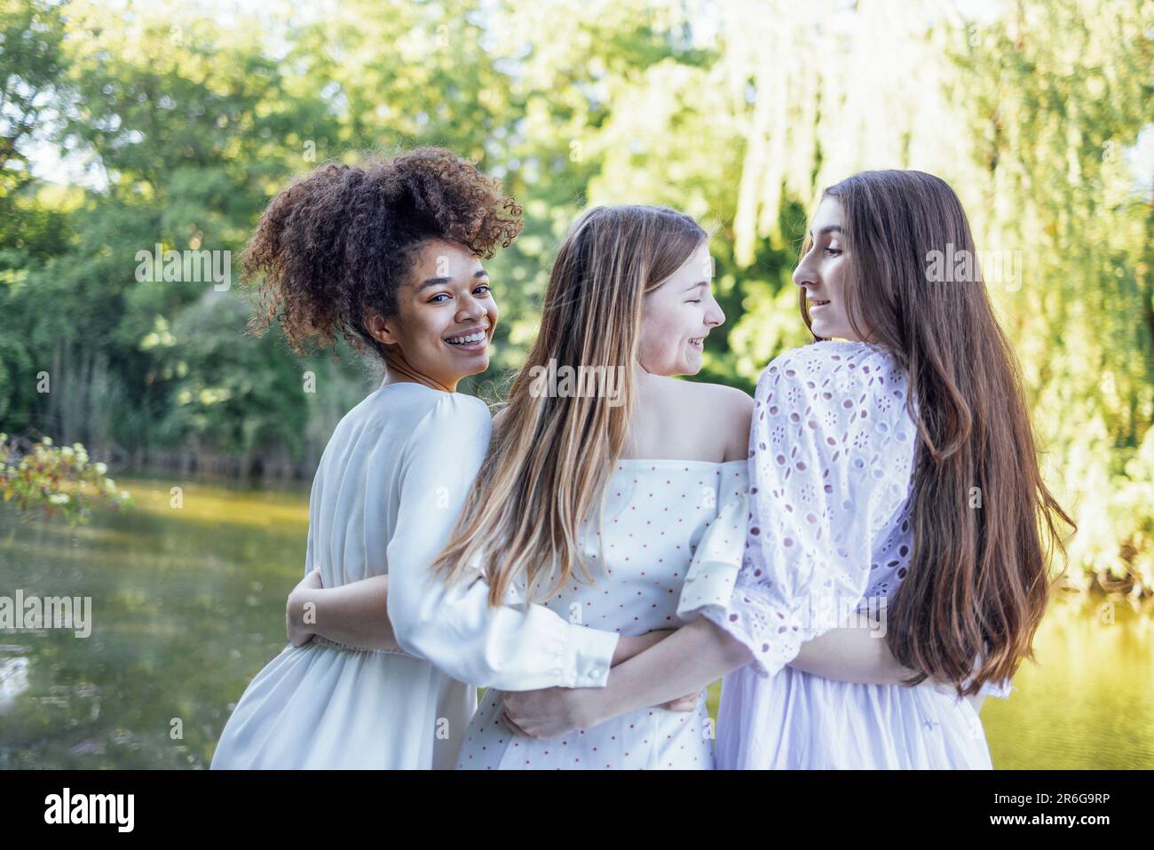 Trois jolies adolescentes multiraciales blanches dans des robes élégantes sont embrassant et riant. Souriante les filles drôles ont beaucoup de temps ensemble. Amitié Banque D'Images