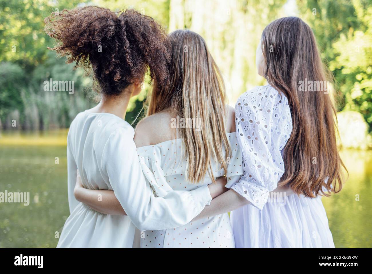 Trois jolies adolescentes multiraciales blanches dans des robes élégantes sont embrassant et riant. Souriante les filles drôles ont beaucoup de temps ensemble. Amitié Banque D'Images