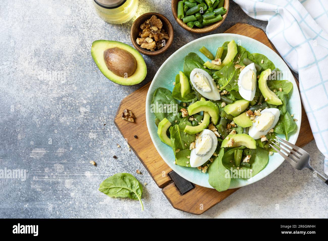 Salade verte bio d'avocat et d'épinards avec œufs, haricots verts, noix sur une table en pierre. Une alimentation saine, une alimentation saine l'été. Vue de dessus. Copier la flèche Banque D'Images