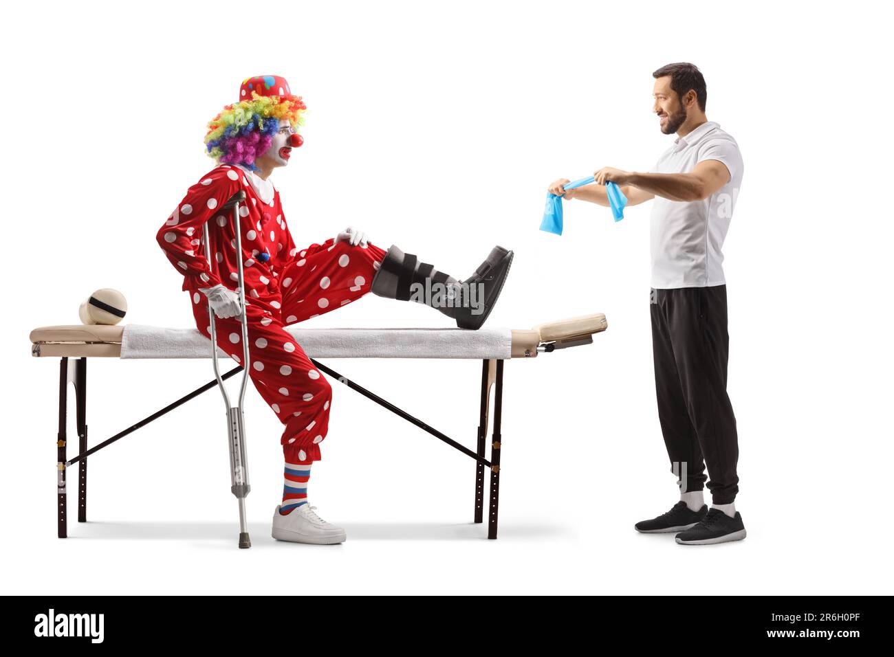 Physiothérapeute montrant l'exercice à un clown avec une jambe blessée isolée sur fond blanc Banque D'Images