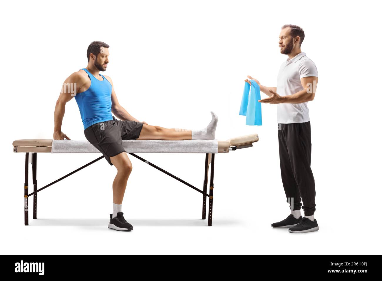 Physiothérapeute montrant l'exercice à un athlète masculin avec une jambe blessée isolée sur fond blanc Banque D'Images