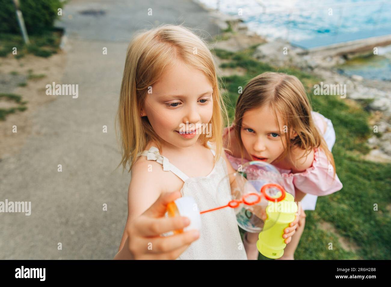 Deux filles drôles jouant avec des bulles de savon à l'extérieur, les enfants s'amusant ensemble Banque D'Images