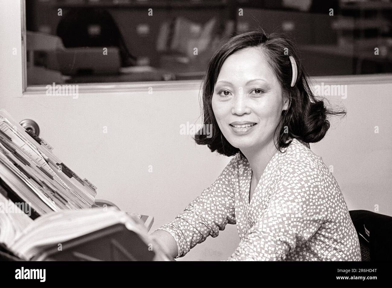 1970S FEMME ASIATIQUE-AMÉRICAINE SOURIANTE TRAVAILLANT DANS UN BUREAU REGARDANT LA CAMÉRA - O4331 HAR001 HARS GAIE FIERTÉ ORIENTALE ASIAN AMERICAN OFFICE WORKER SUPERVISOR OCCUPATIONS SOURIT GAL FRIDAY ADMINISTRATOR JOYFUL SECRÉTAIRES STYLÉES AMANUENSIS ASIAN-AMERICAN MANAGERS FEMME MOYENNE-ADULTE SUPERVISEURS NOIR ET BLANC CLÉRICAL HAR001 À L'ANCIENNE Banque D'Images