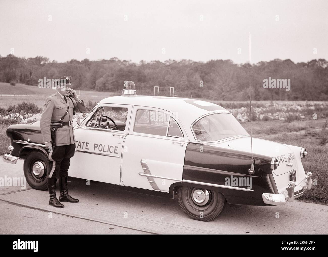 1950S VOITURE DE PATROUILLE DE LA POLICE D'ÉTAT DU NEW JERSEY TROOPER EN UTILISANT UN TÉLÉPHONE PORTABLE PARLEZ AU SIÈGE D'AUTRES VOITURES OU À L'AVION DE TÊTE DU NEW JERSEY USA - Q54353 CPC001 CARRIÈRE HARS SERVIR LA TECHNOLOGIE DE SÉCURITÉ DES VÉHICULES INFORMATION SUR LA SÉCURITÉ FORD STYLE DE VIE TRAVAUX DE TÊTE COMMUNIQUANT ESPACE DE COPIE PLEINE LONGUEUR HIGHWAY PERSONNES INSPIRATION AUTOMOBILE HOMMES ORDRE MÉTIER CONFIANCE TRANSPORT B&W COP COMPÉTENCE MÉTIER PROTÉGEZ LES COMPÉTENCES AVENTURE GRAND ANGLE ET AUTOS CARRIÈRES LEADERSHIP EXTÉRIEUR PROGRÈS FIERTÉ OPPORTUNITÉ AUTORITÉ OCCUPATIONS TÉLÉPHONES UNIFORMES UTILISATION DE LA PATROUILLE DE CONNEXION TÉLÉPHONES CONCEPTUELS AUTOMOBILES Banque D'Images