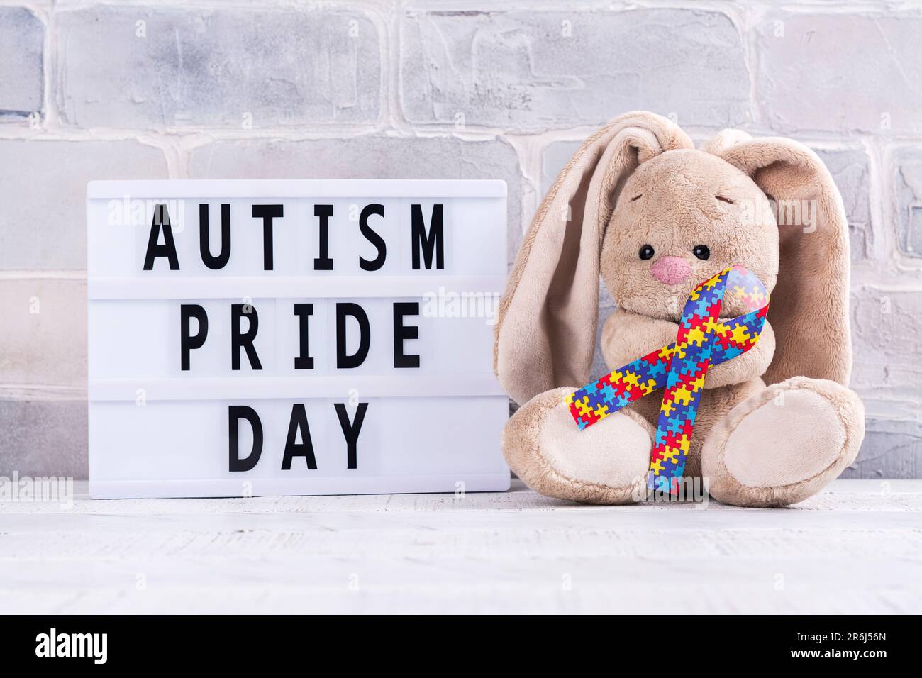 Journée Mondiale De Sensibilisation Et De Fierté à L'autisme Ruban De Motif  De Puzzle Et Lapin Jouet Sur Fond Jaune Image Verticale